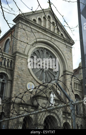 Razor wire atop fence, the Shrine Church of Saint Anthony of Padua in background. SoHo (Greenwich Village), Manhattan, New York Stock Photo