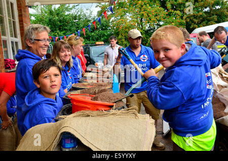Burrowbridge, Somerset, UK. 9th August, 2014. UK weather:  An Emergency call out for local helpers to make more sandbags to be put in place around the bridge and along the Main Road opposite due to very bad weather forecast Moving in Picture Shows, Seth left and Ryan right Helping. Credit:  Robert Timoney/Alamy Live News