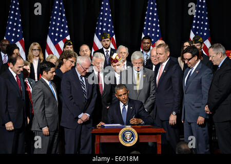 US President Barack Obama signs into law a bill to overhaul the Department of Veterans Affairs as members of congress look on August 7, 2014 in Fort Belvoir, Virginia. Stock Photo