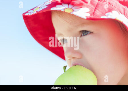 child girl eating big green apple closeup outdoor Stock Photo