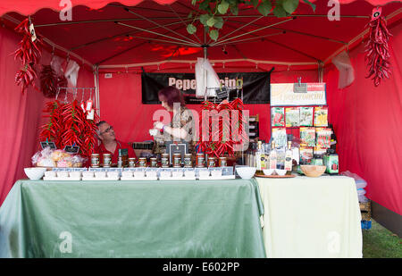 West Dean, Chichester, UK. 9th August, 2014. A couple man their stall at the start of the Chilli Fiesta at West Dean, comprising of hanging red peppers, and bottles of chilli sauce and chutney. Credit:  MeonStock/Alamy Live News Stock Photo