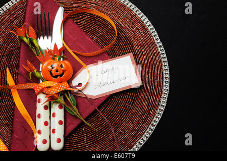 Happy Halloween table place setting with red polka dot cutlery and pumpkin decorations. Stock Photo