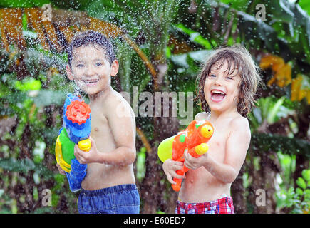 Boys spraying with water pistols in heat wave Stock Photo