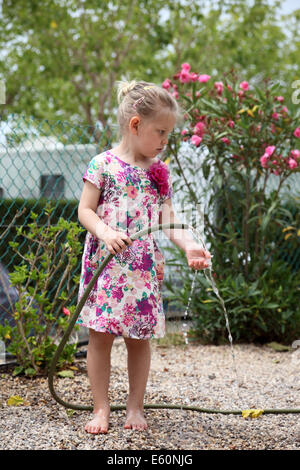 Little girl playing with water hose in the garden Stock Photo