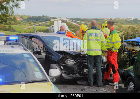 Bexhill, East Sussex, UK.10th August 2014. Emergency Services in action after a Road Traffic accident on the A259 , Barnhorn Road, West of Little Common. A lady was taken from the scene by road ambulance Police advised her injuries were not serious, helicopter evacuation was not required by Kent HEMS which was quickly on site. Locals at the scene advise that this is a regular accident Black spot.. David Burr/Alamy Live News