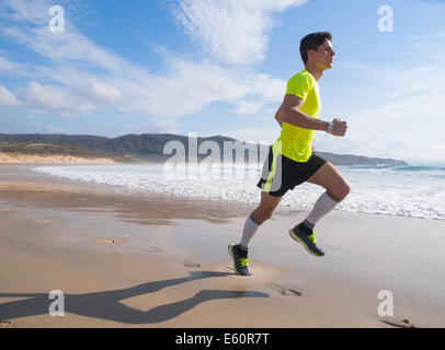Young Man In Fitness Clothing Running Along Beach outdoors Stock Photo