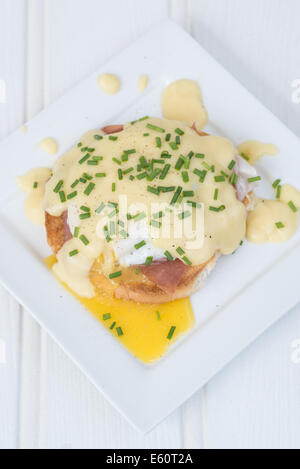 Eggs Benedict toasted English muffins ham poached eggs and delicious buttery hollandaise sauce Stock Photo