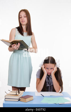 Teacher standing at desk behind which sits a tired student Stock Photo ...