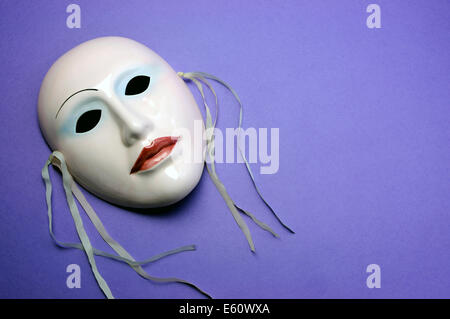 Pale pink ceramic mask on purple background for actor, performance or theater concept with copy space for your text here. Stock Photo