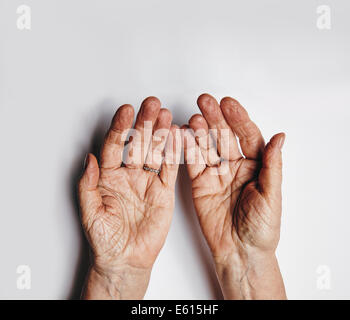 Top view of two empty female hands over grey background. Senior woman hands pleading. Wrinkled palms of aged woman with copy spa Stock Photo