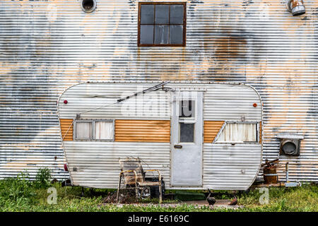 Dilapidated caravan made of corrugated iron parked in front of a corrugated iron wall, rusty chair at the front, Clarksdale Stock Photo