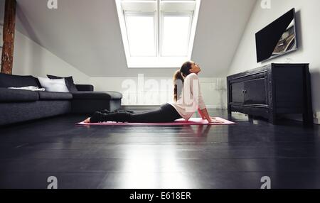 Young brunette woman working out stretching exercise on floor. Fitness female model exercising on mat at home. Stock Photo