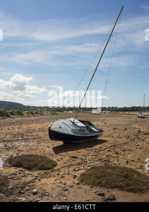 A sailing boat stranded by the receding tide in Red Wharf Bay, Anglesey, Wales, GB. The yacht lies high and dry on the sandy beach in Anglesey, Wales. Stock Photo