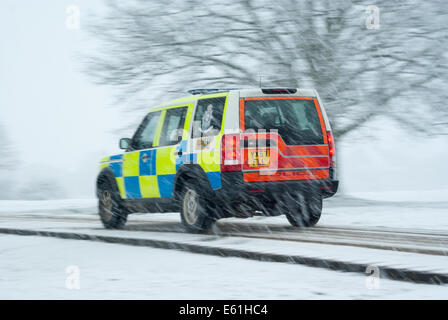 A highly visible Police Land Rover Discovery 4x4 driving on a snowy road in dangerous conditions Stock Photo