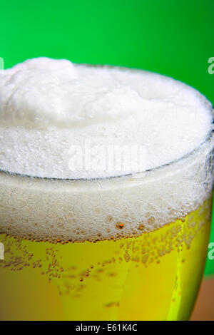 Glass of beer with froth close-up over green background Stock Photo