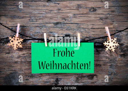 A Green Hanging Tag with the German Words Frohe Weihnachten which means Merry Christmas on wooden Background Stock Photo