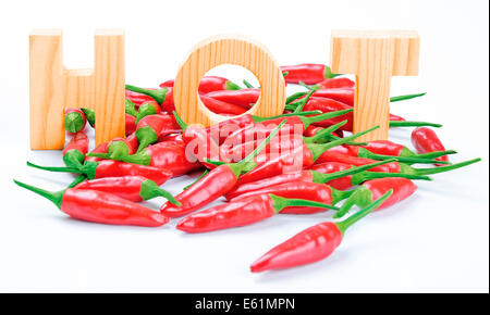 Chilies And HOT Wooden Letters - Red fresh chilies with three wooden letters writing the word HOT. Stock Photo