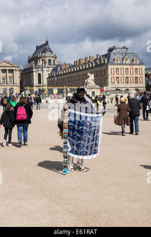 Migrant street vendor sells souvenirs outside the Palace of Versailles [ Chateau de Versailles ] in France Stock Photo