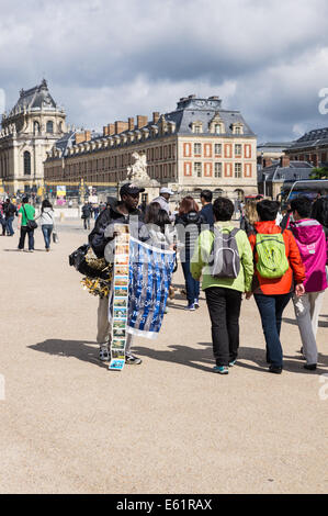 Migrant street vendor sells souvenirs outside the Palace of Versailles [ Chateau de Versailles ] in France Stock Photo