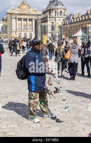 Migrant street vendor sells souvenirs outside the Palace of Versailles [ Chateau de Versailles ] in France Stock Photo