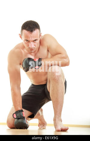 concentrated  angry martial fighter with fight gloves pray for victory while kneeling down and looking at camera Stock Photo