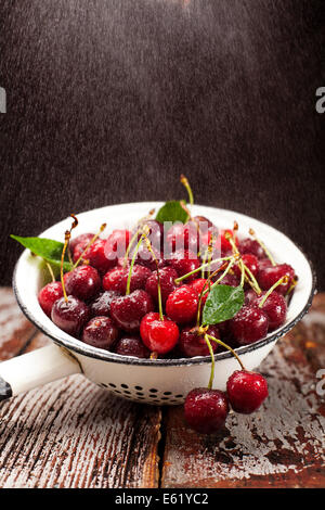 Fresh red cherries being washed in colander. Stock Photo