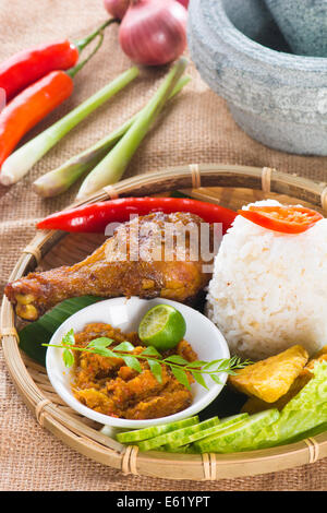 Famous traditional Indonesian food. Delicious nasi ayam penyet with sambal belacan. Fresh hot with steam smoke. Stock Photo