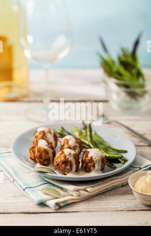 Tasty meatballs in white sauce with sage and green beans Stock Photo