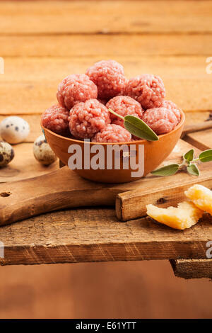 Raw meatballs with sage on warm wooden background Stock Photo