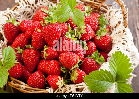 Strawberries in basket on rustic wooden background Stock Photo