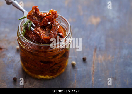 Sun-dried tomatoes in jar on wooden background Stock Photo