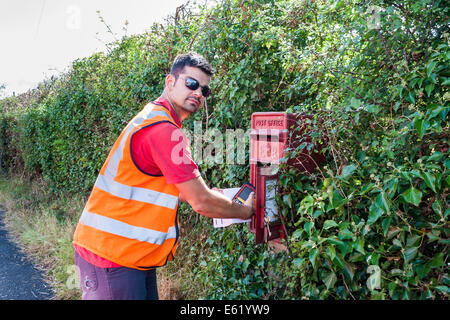 Royal Mail postman collects mail from rural pillar box Stock Photo