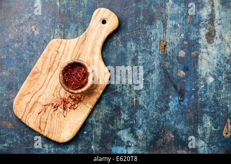 Saffron in olive wood bowl on blue wooden background Stock Photo