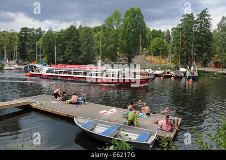 Sightseeing boats and kayakers on Langholmen Långholmen Canal with sunbathers in Stockholm Stock Photo