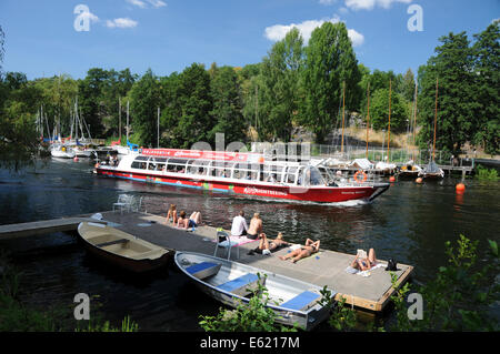 Sightseeing boats and kayakers on Langholmen Långholmen Canal with sunbathers in Stockholm Stock Photo