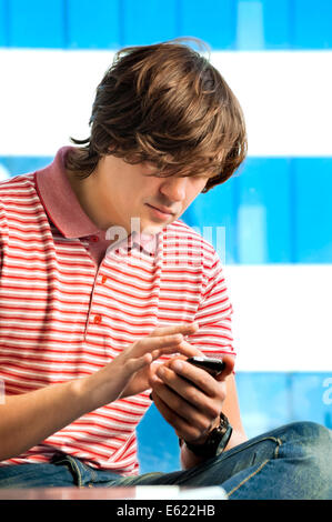 Portrait of a trendy young guy typing a message on mobile phone Stock Photo