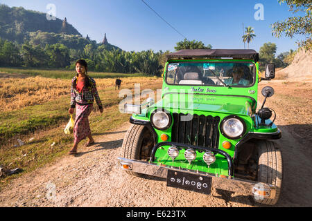 Woman walking next to a four-wheel drive vehicle, Jeep on a dirt road, Mrauk U, Sittwe District, Rakhine State, Myanmar Stock Photo