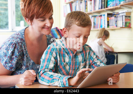 School Pupil With Teacher Using Digital Tablet In Classroom Stock Photo