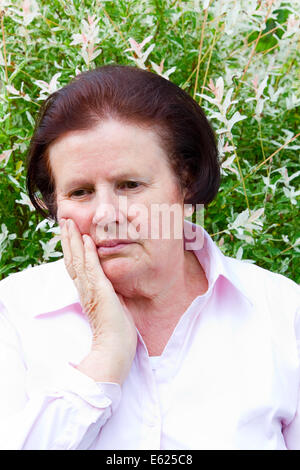 Elderly woman with toothache holding her cheek Stock Photo