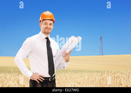 Male engineer holding construction plans In a field on a sunny day Stock Photo