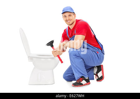 Male plumber sitting next to a toilet and holding a plunger Stock Photo