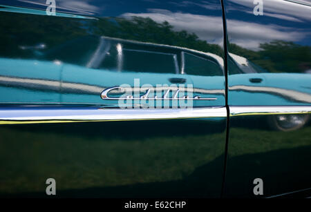 Chrome Cadillac badge and trim with a blue Ford Chevrolet reflected in the black paint work Stock Photo