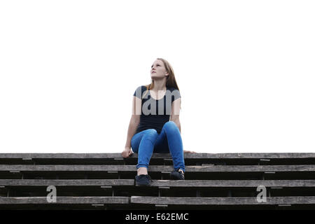 pensive young woman sitting on outside flight of stairs Stock Photo