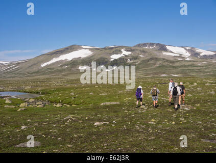 Hikers on a footpath across Valdresflya in Jotunheimen Norway, barren but inviting in the summer sun, heading for the National park Stock Photo