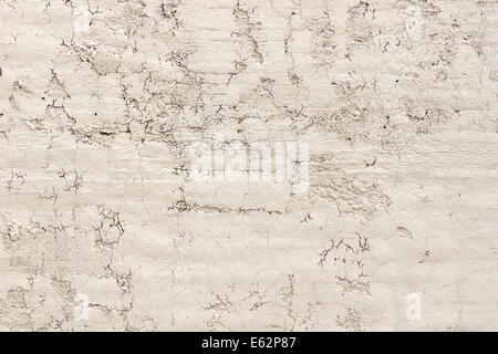 Close view of an old weathered stucco wall with cracks and damage. Stock Photo