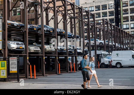 Manhattan, New York. People Pass by multi-story parking lot. Stock Photo