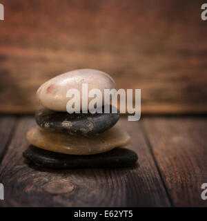 Pebbles stack on wooden background, in low light setting with vintage filter. Stock Photo