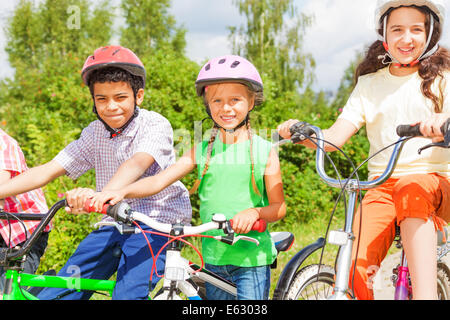 Three kids in helmets sitting on the bikes Stock Photo