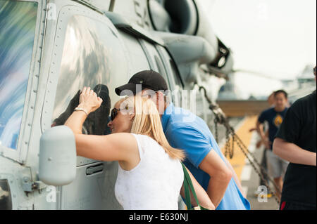 A couple admire the cockpit of a Sikorsky SH-60 Seahawk aboard the USS Essex. Stock Photo