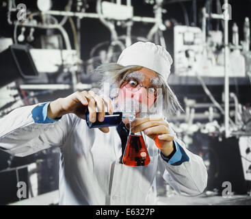 1970s MAN CRAZY LOONY MAD SCIENTIST CHEMIST IN LABORATORY POURING CHEMICALS FROM ONE BEAKER TO ANOTHER Stock Photo